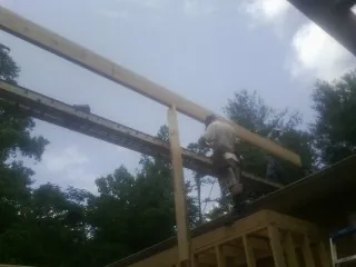 Carpenter setting a ridge beam over a new addition frame — Ice Dam Removal by Roofing Brothers in Patrick