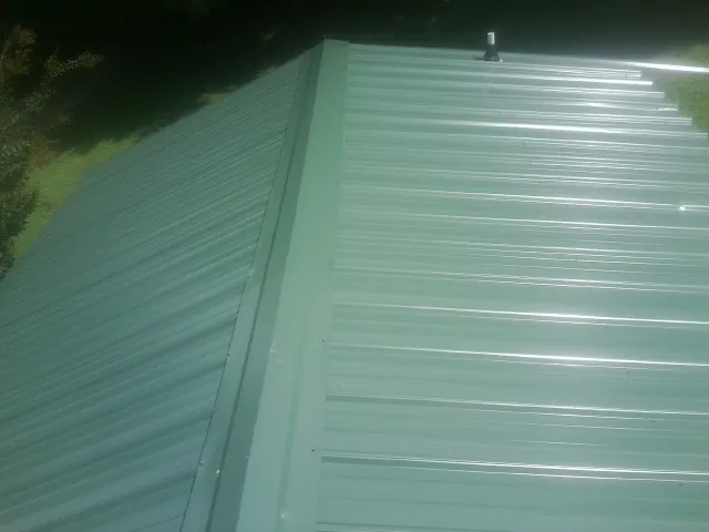 New green metal panels meeting at the ridge of a roof — Flat Roof Repair work by our crew in Patrick