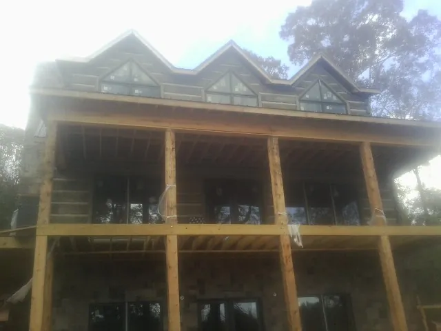 Dormers and porch framing on a large log home under construction — Roof Coating work by our crew in Patrick