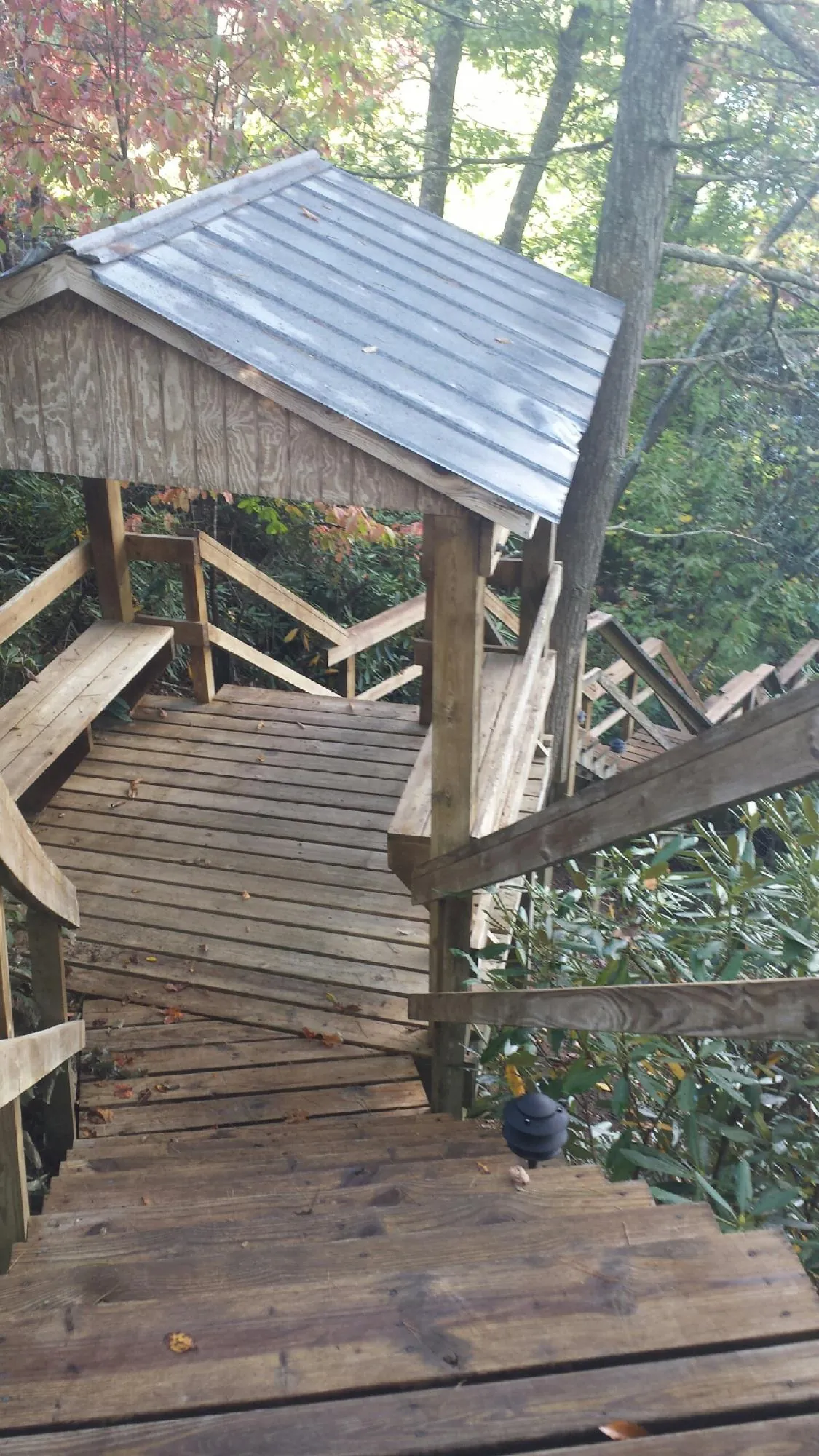 Metal roofed shelter over wooden steps on a wooded walkway — Skylight Repair & Installation work by our crew in Patrick