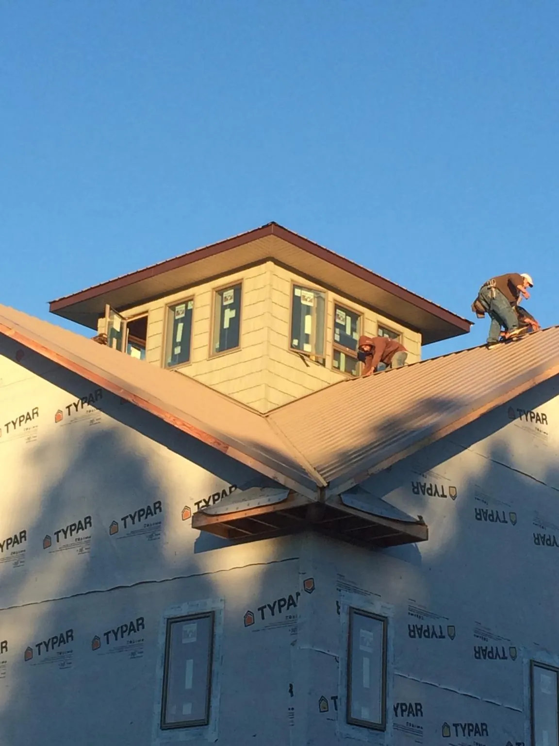 Roofers working around a rooftop cupola on a new metal roof at sunset — Roof Waterproofing in Patrick by Roofing Brothers